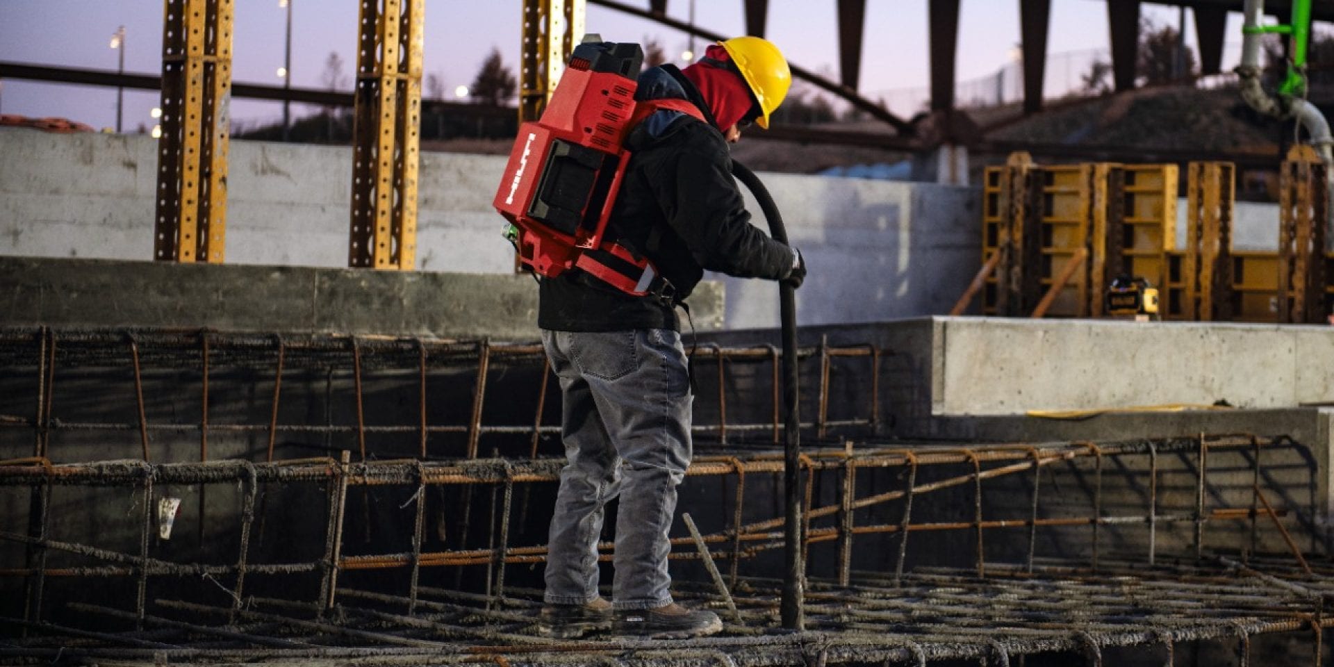 Jobsite worker using Hilti NCV 10-22 concrete vibrator during casting